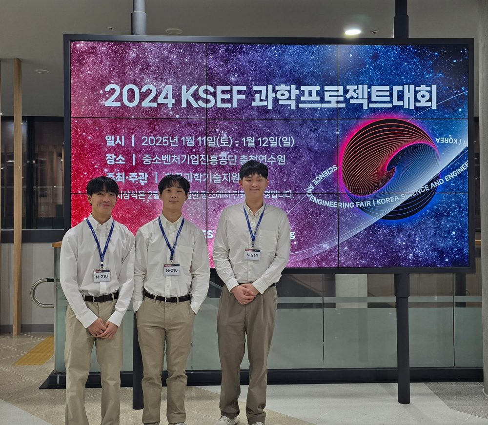 Jayden and two teammates in front of the 2024 KSEF screen